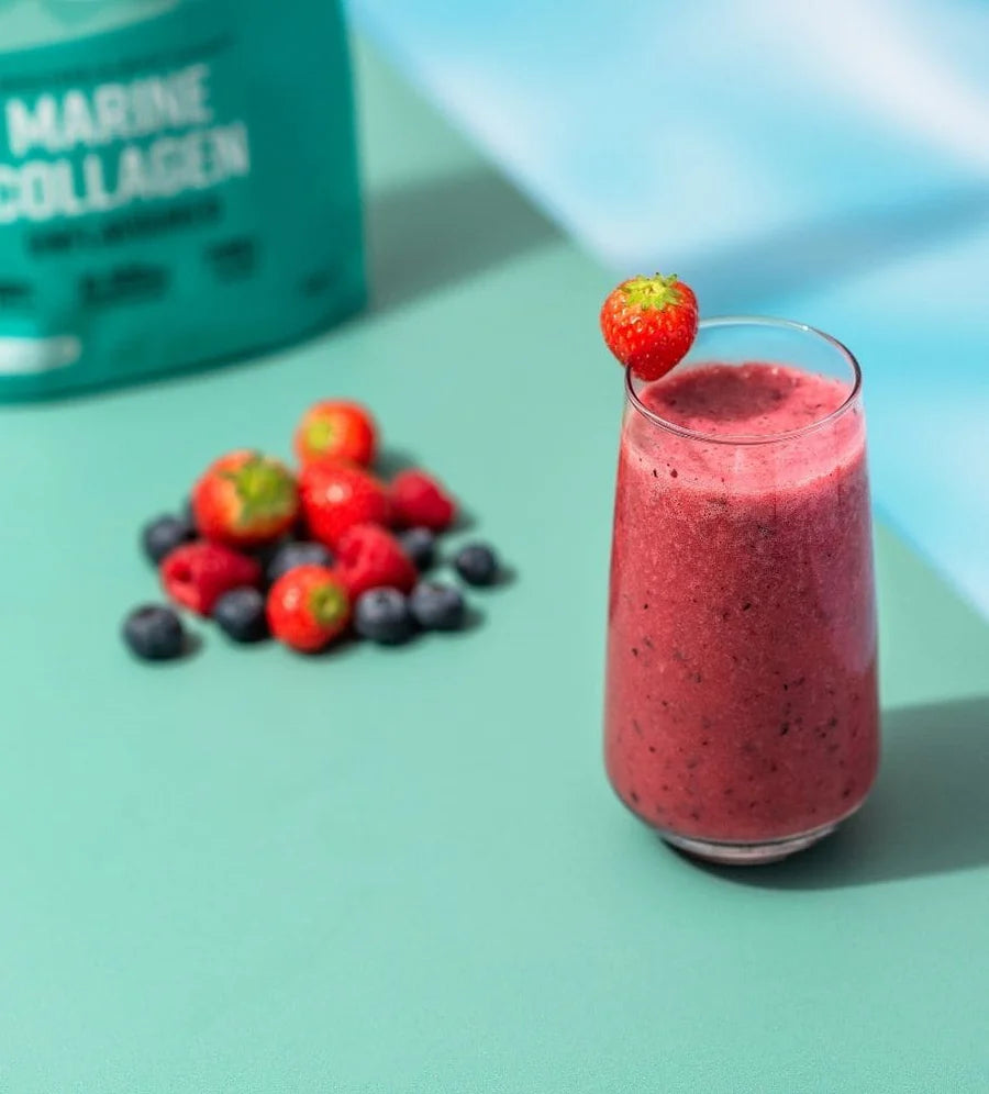 Glass of red smoothie with berries on a light blue background